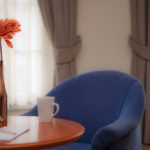 blue chair with a table that has a flower and cup