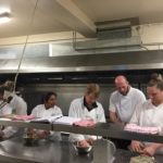 head chef teaching in the kitchen with a group of ladies in whites