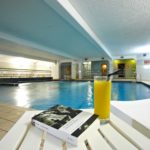 swimming pool with glass of orange juice and book