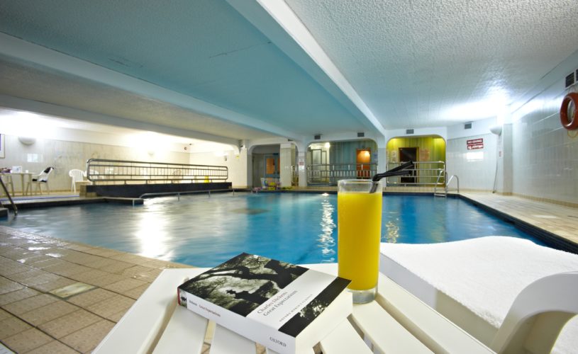 swimming pool with glass of orange juice and book