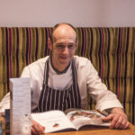 man sat at table in chef whites