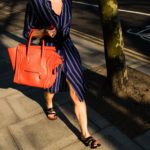 lady walking with blue dress and orange bag on her arm