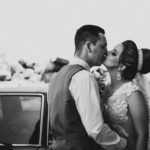 a married couple kissing in front of a car