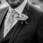 a groom with flowers on his jacket