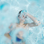 boy with goggles swimming in pool