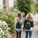 two girls with back packs walking in green land
