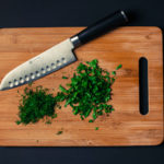 knife and herbs on a wooden chopping board