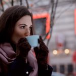 lady drinking coffee outside in the cold with scarf