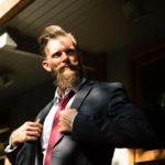 man in suit with large amount of facial hair and red tie