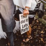 man and lady stood with sign saying lets party