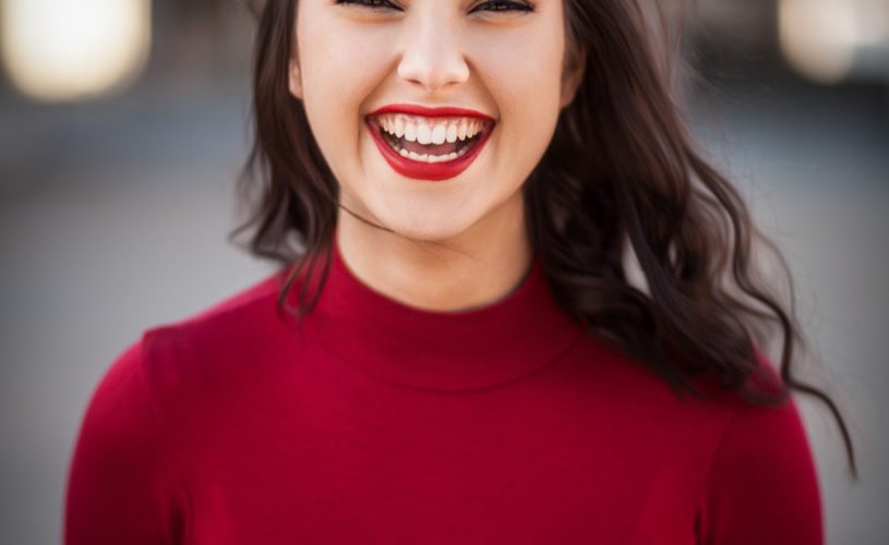 lady in red top with brown hair and red lips